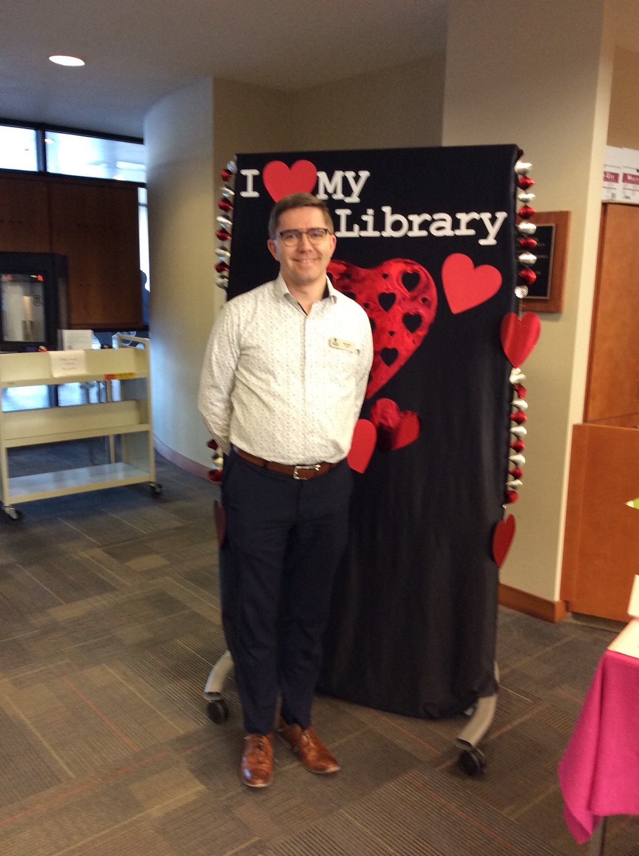 Associate University Librarian for Content Management and Discovery Dale Storie stands in front of the I love my library backdrop with his hands behind his back, smiling